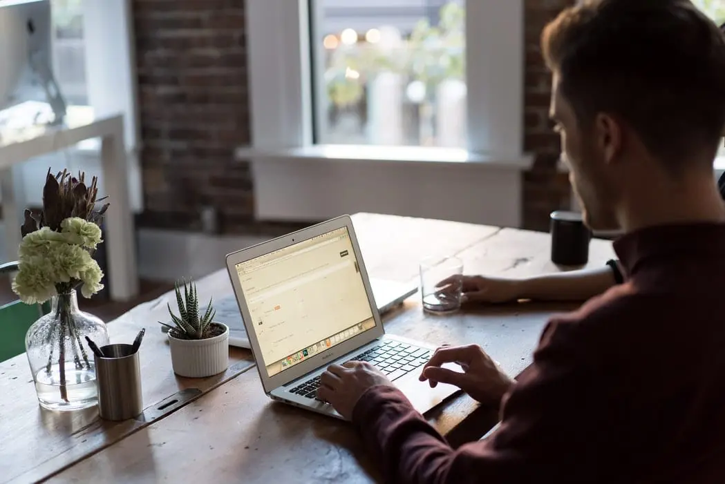Man sitting at desk and typing on laptop.