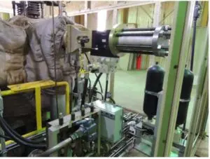 Picture1 A hydraulic press system in an industrial setting, showing cylinders, pipes, and control components, with insulation-covered equipment on the left and two black pressure vessels on the right.