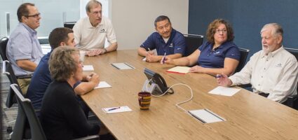 Employees having a team meeting around a conference table.