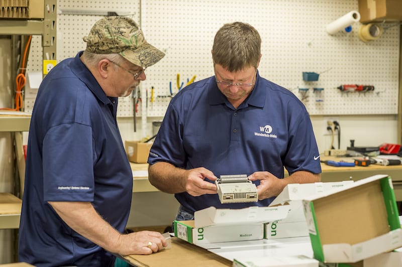 Two Wunderlich-Malec employees working on a piece of equipment.