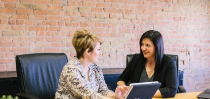 Two business woman sitting at a desk.