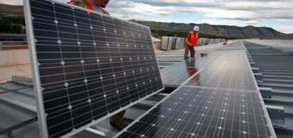 Two workers installing solar panels.