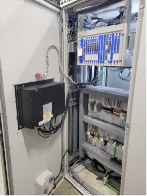 An open electrical control panel showing various electronic components, wiring, circuit boards, and connectors neatly arranged inside a metal enclosure.