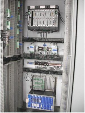 An industrial control panel with multiple electronic modules, circuit boards, and wiring neatly organized inside a metal cabinet, used for monitoring and controlling automated systems.